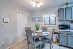 A compact kitchen with a dining area, featuring a microwave, cabinets, and a dining table with chairs.