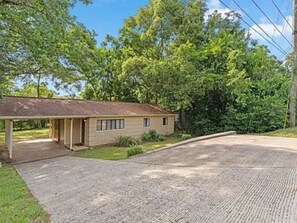 A single-story house with a covered porch, a driveway, and a lawn.