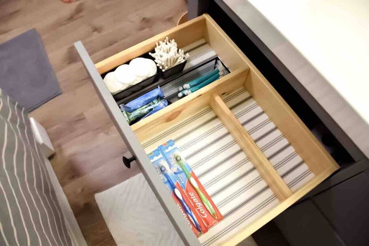 Un cajón con compartimentos organizados que contiene cepillos de dientes, pasta dental y otros artículos de aseo.