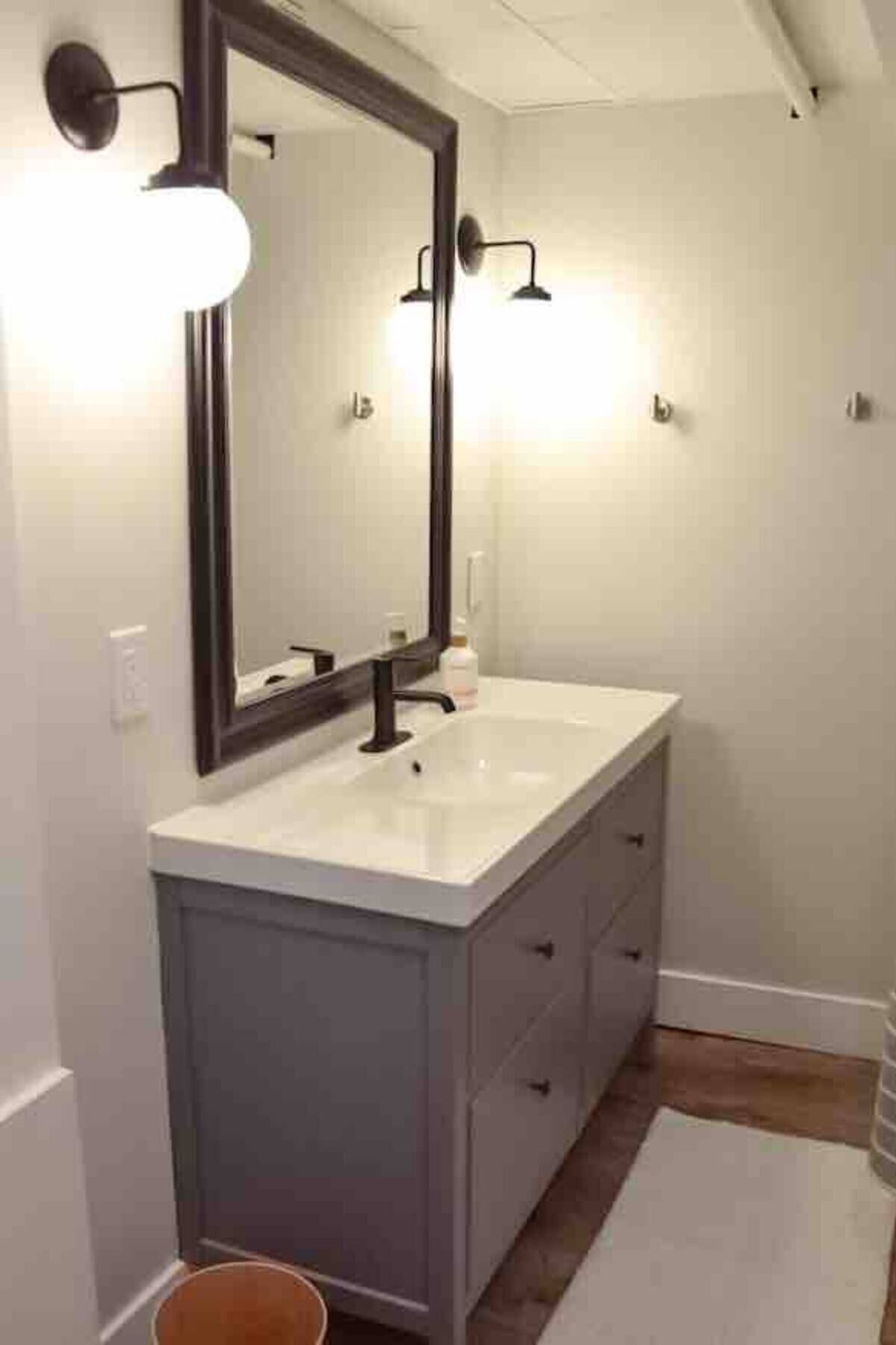 A bathroom with a white vanity, a large mirror, and two wall-mounted lights.