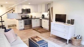 Una cocina moderna con gabinetes blancos, electrodomésticos de acero inoxidable y un televisor de pantalla plana.