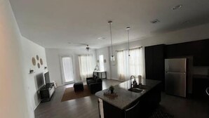 Una cocina moderna con una isla central, muebles oscuros y un refrigerador de acero inoxidable.
