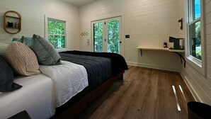 Une chambre à coucher avec un lit, deux fenêtres, un ventilateur de plafond et une étagère près de la fenêtre.