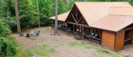 Eine Holzhütte mit überdachter Veranda, einer Holzterrasse und einer Sitzgelegenheit im Freien.
