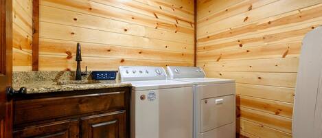 A compact kitchen with wooden walls, a granite countertop, a stove, and a washing machine.