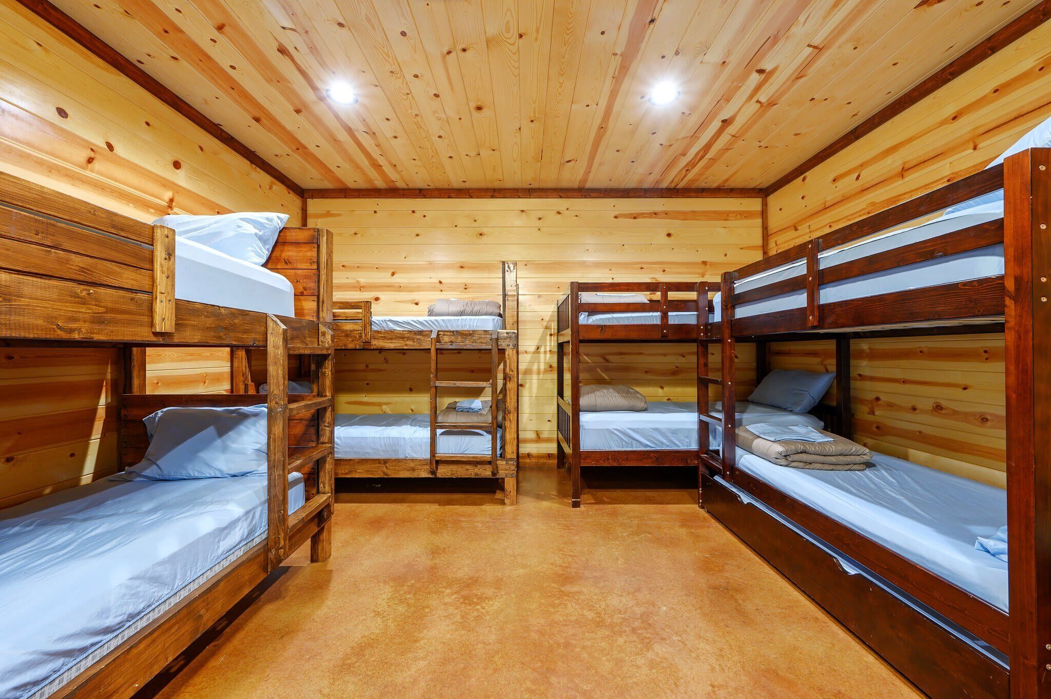 Eine Holzhütte mit drei Etagenbetten, Holzwänden und Teppichboden.