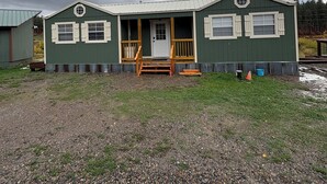 A single-story building with a porch, a front door, and a small set of steps leading up to the entrance.
