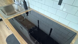 A kitchen with a black countertop, stainless steel sink, and a black stove.