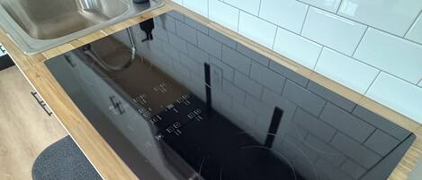 A kitchen with a black countertop, stainless steel sink, and a black stove.