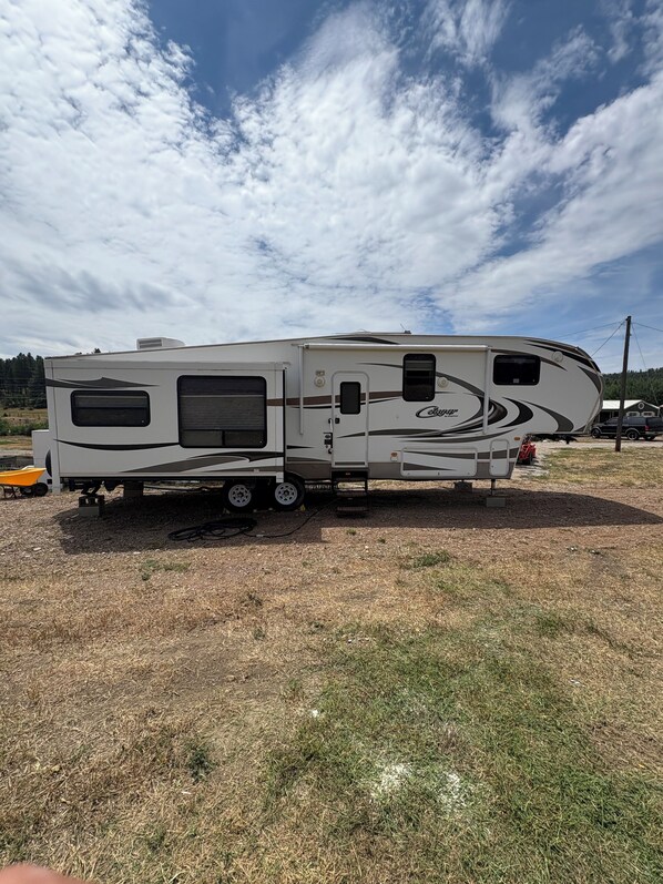 A large RV with a covered living area, a kitchen, and a sleeping area. - Cool RV with AC in Bayfield next to small lake (Bayfield)