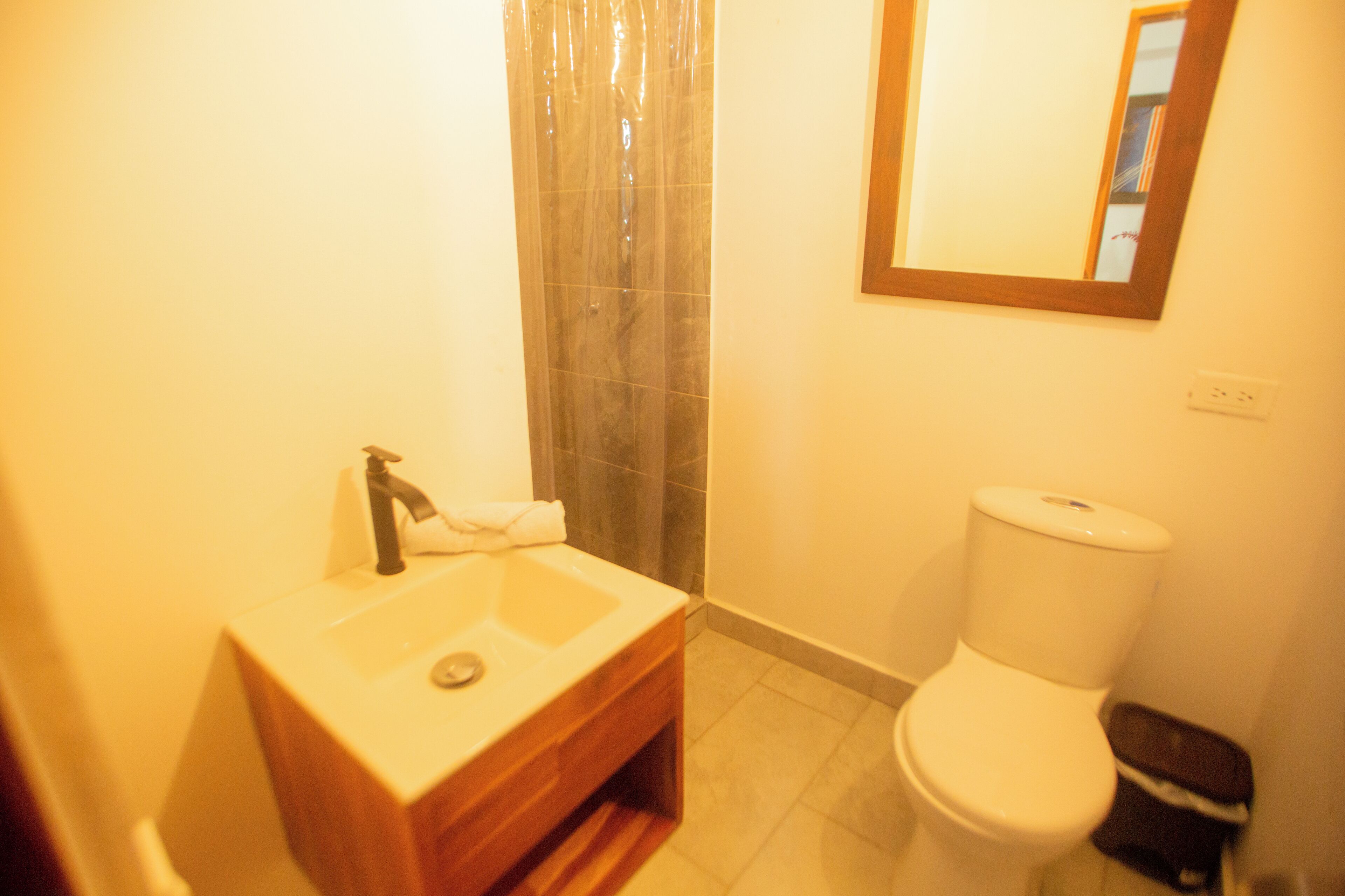 A bathroom with a wooden vanity, a toilet, and a shower with a glass door.