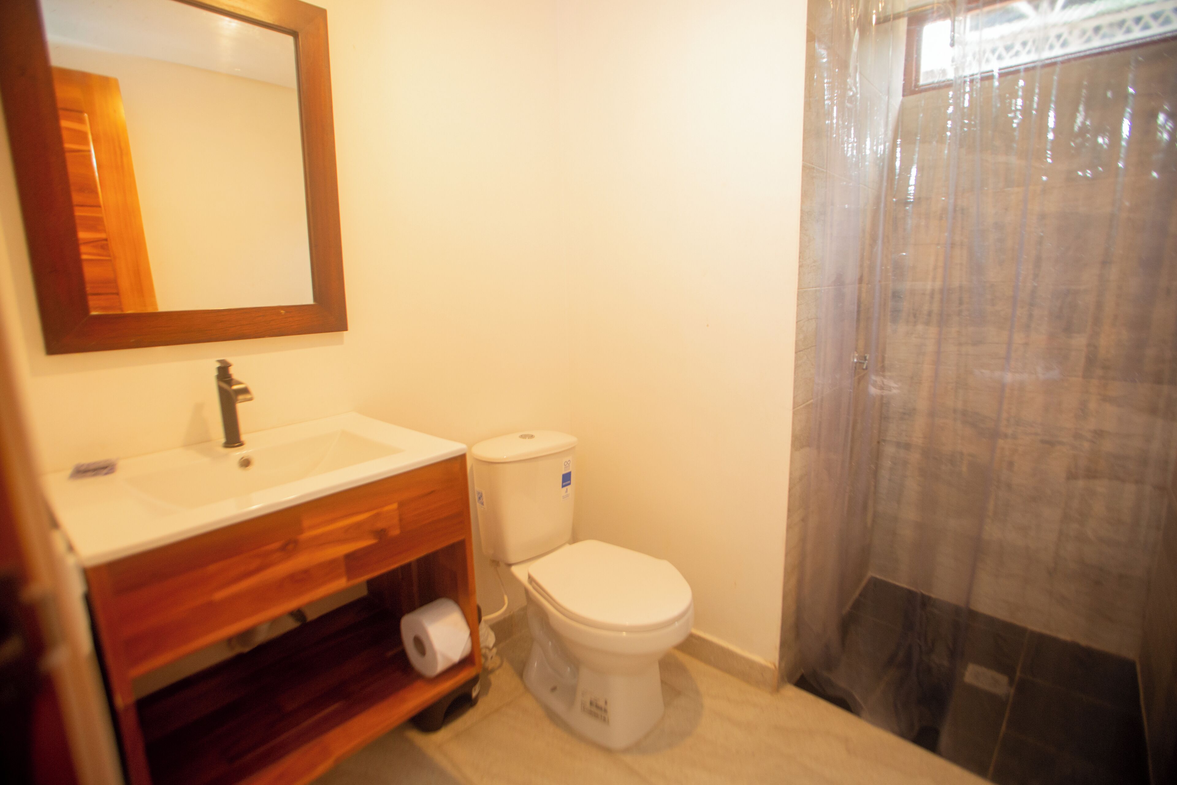 A bathroom with a wooden vanity, a white sink, a toilet, and a shower curtain.