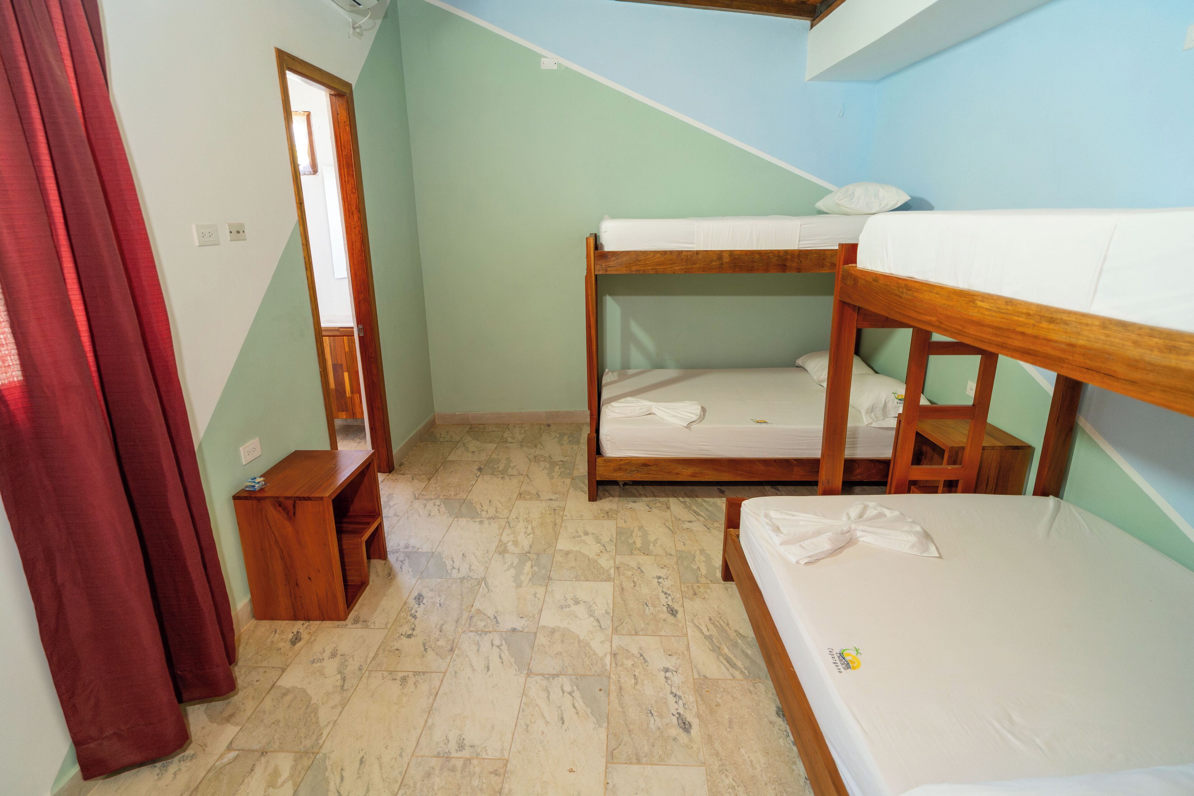 A small, compact room with a bunk bed, a wooden bench, and a mirror.
