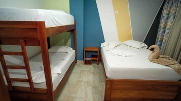 Una habitación con literas, una cama individual, un taburete de madera y una cortina.