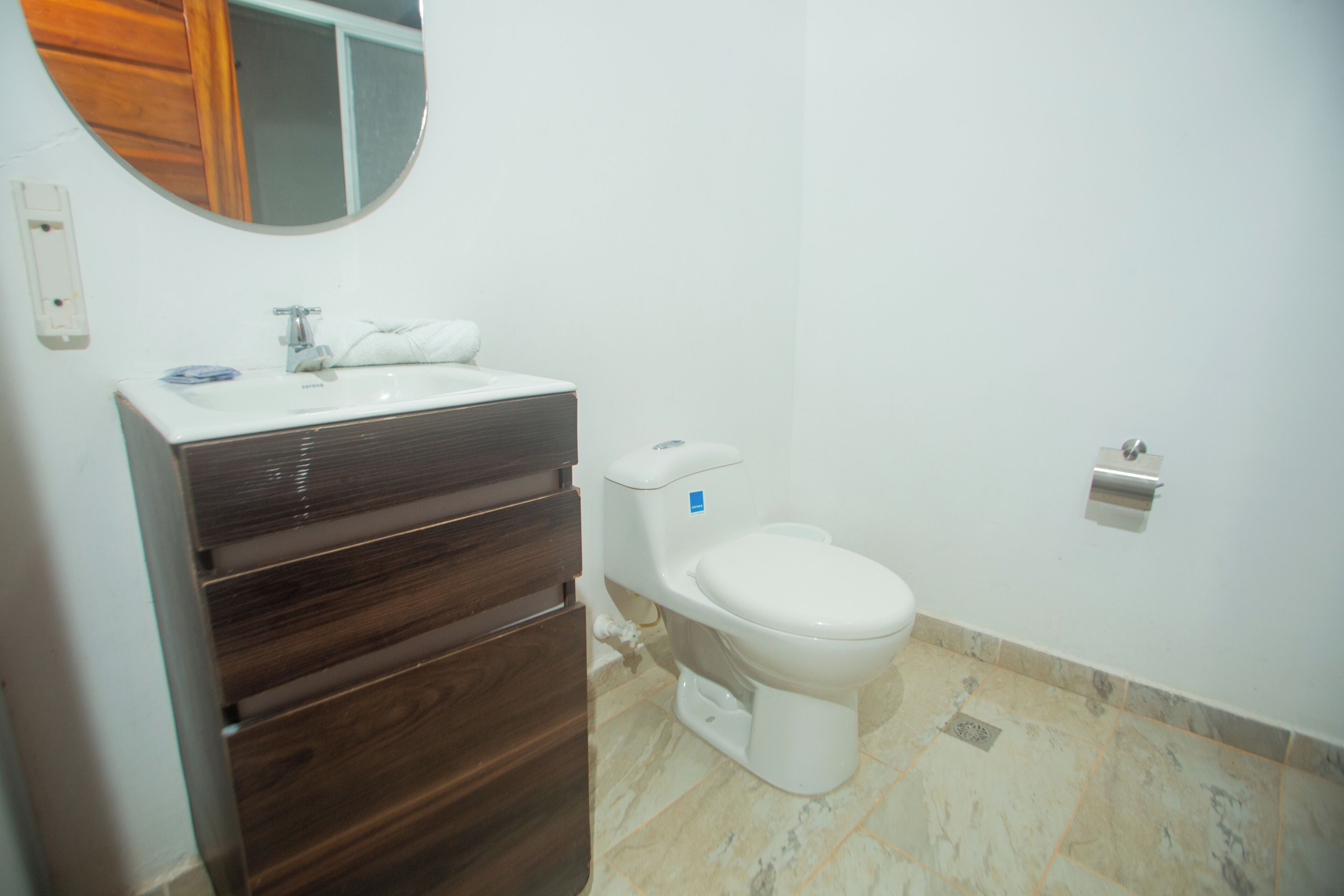 A bathroom with a white sink, dark wooden vanity, a white toilet, and a mirror above the sink.