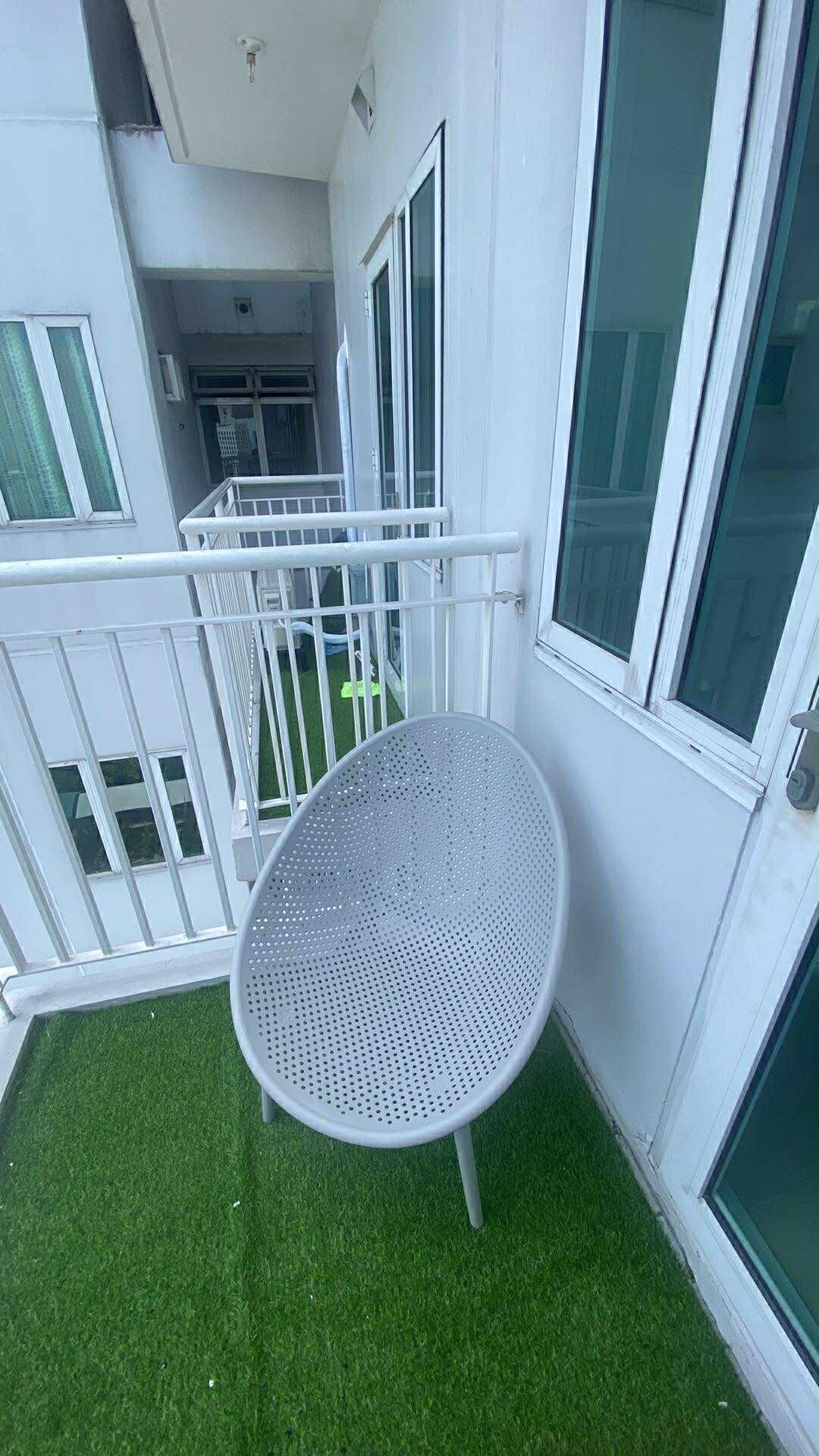 Un balcone con un tavolo in metallo e una piccola area di erba sintetica.