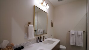 A modern bathroom with a white sink, a large mirror, and a shower area. - Brand new 2-bedroom home in the heart of Kennewick (Kennewick)