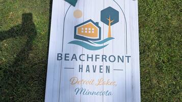 Um letreiro com tema praiano, com um ícone de casa e árvore, com a inscrição 'Beachfront Haven, Detroit Lakes, Minnesota'.