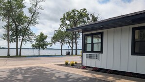 Un bâtiment d’un seul étage, doté d’un petit porche, d’une fenêtre avec une grille d’aération et offrant une vue sur un lac.