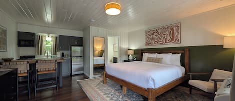 A bedroom with a large bed, a wooden headboard, a nightstand, a lamp, and a mirror.