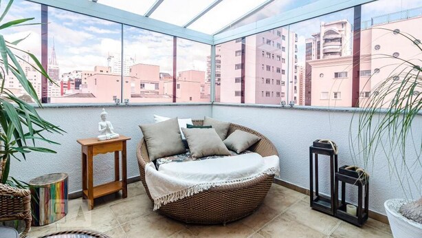 A balcony with a wicker sofa, a small table, and a potted plant.