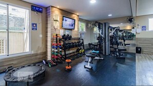 A gym with exercise equipment, a TV, and a digital clock.