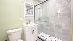 A modern bathroom with a toilet, sink, and glass-enclosed shower.