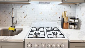 A kitchen with a white stove, a sink, and a knife block.