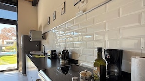 A modern kitchen with a black countertop, stainless steel appliances, and a view of the outdoors.