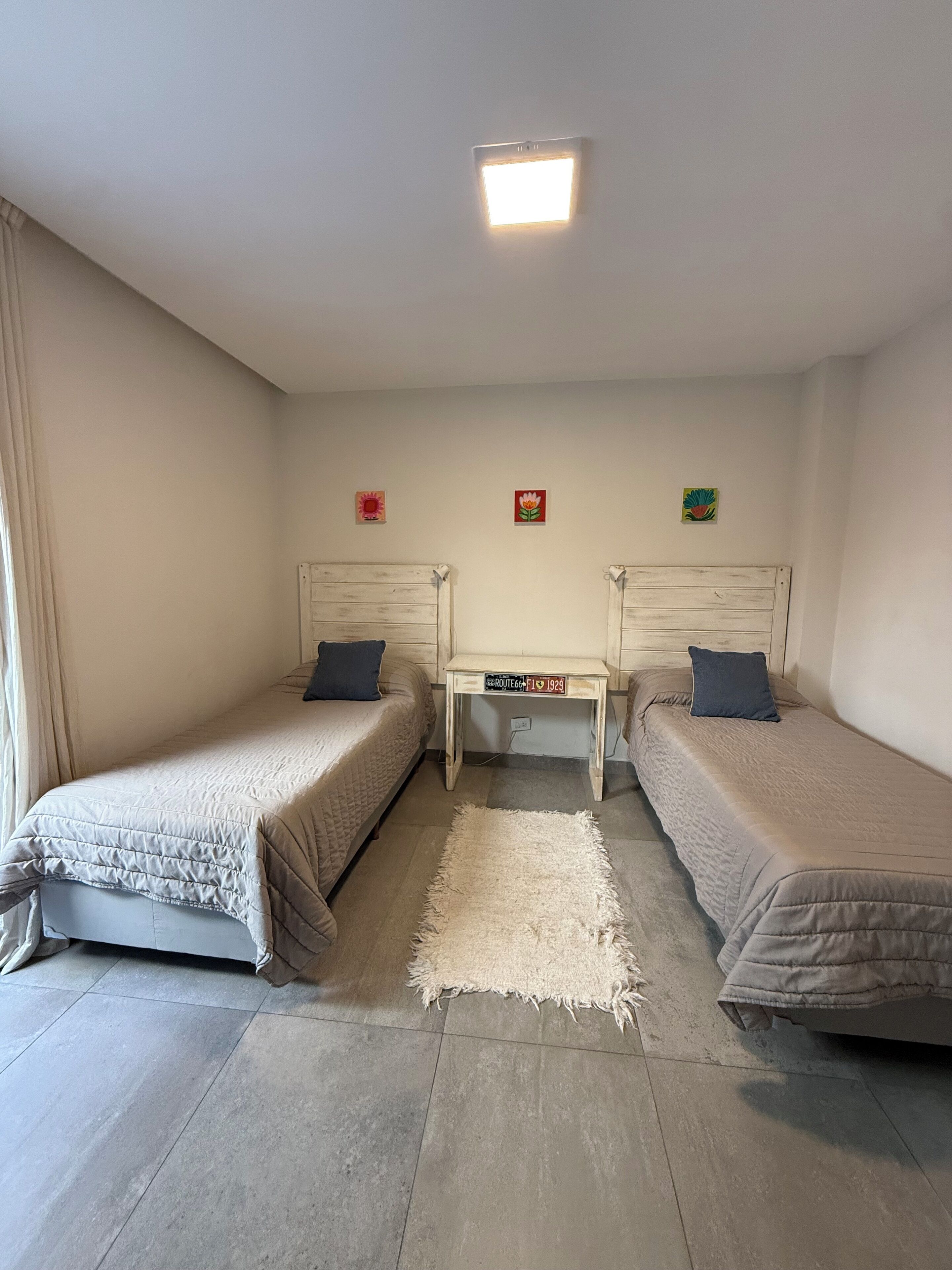 A room with two beds, a small table, and a ceiling light.