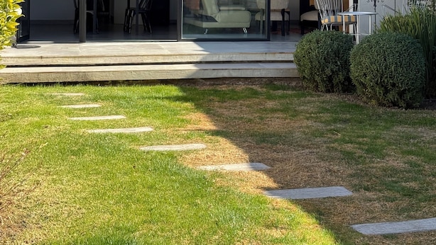 A modern house with a glass-enclosed patio, a dining area, and a small garden.