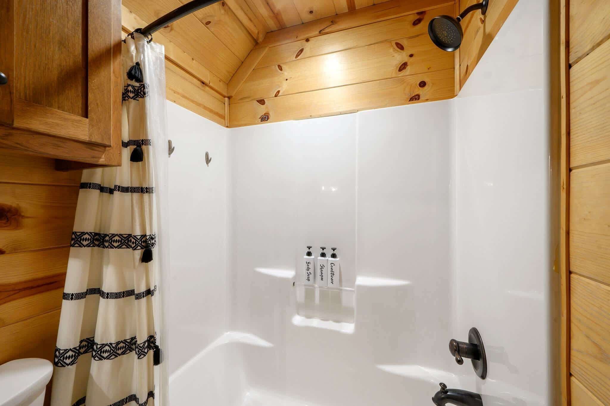 Een houten badkamer met een douche, toilet en handdoekrek.