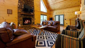 Un acogedor interior de cabaña de madera con chimenea de piedra, mobiliario de cuero y un ventanal grande.