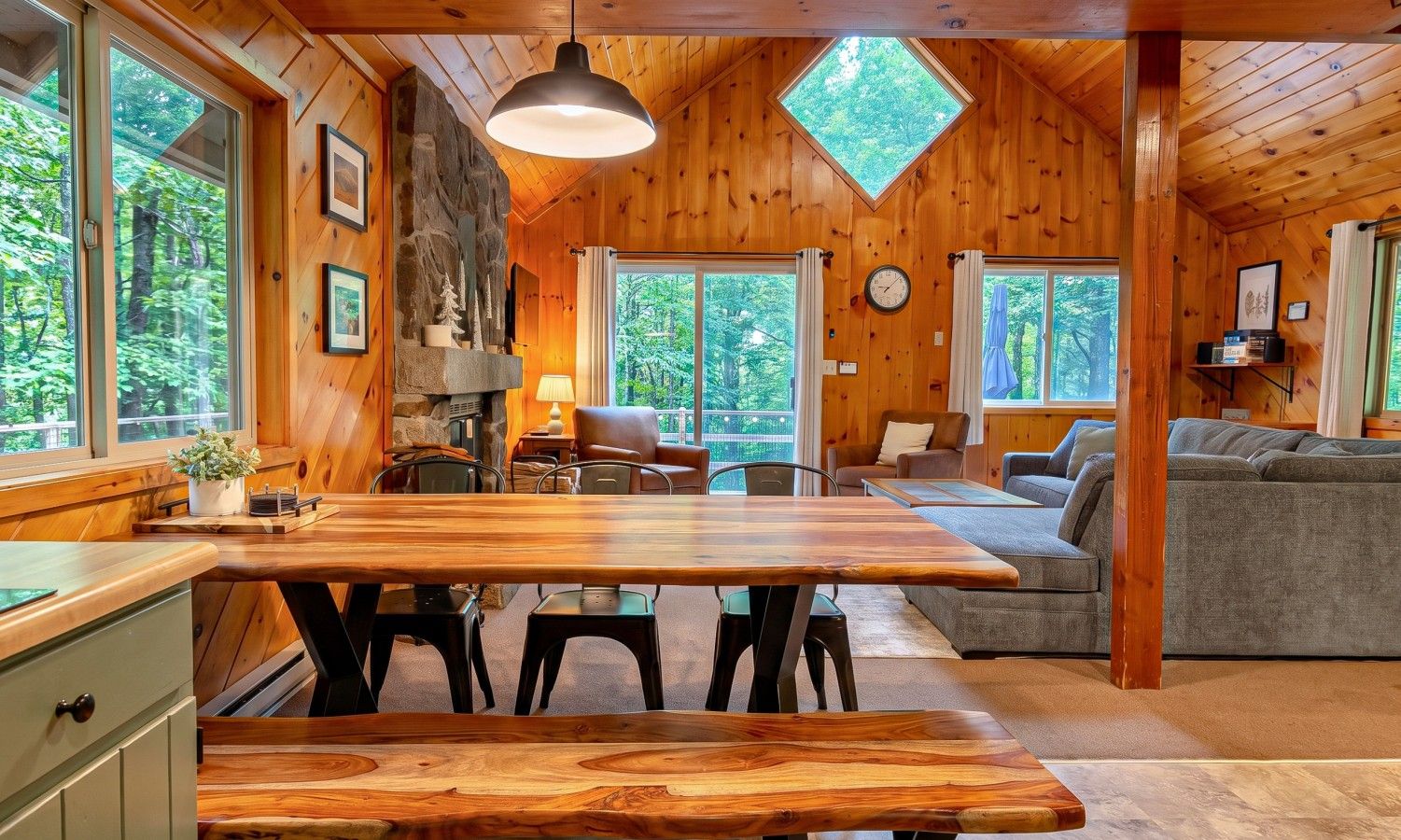 L’intérieur d’un chalet en bois comprend un coin repas, un canapé et une cheminée en pierre.