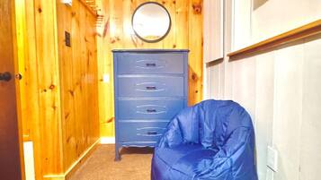 Een kamer met een houten wand, een blauwe kruisje zitzak en een dressoir met lades.