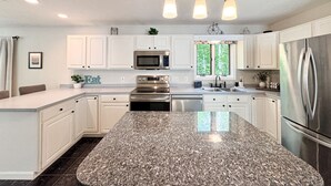 A modern kitchen with white cabinets, stainless steel appliances, a granite countertop, and pendant lighting. - Stylish comfort, great location (Bartlett)