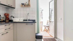 Una cocina moderna con armarios blancos, encimera negra y ventana con vistas a un balcón.