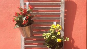 Two metal planters with red and yellow flowers on a wooden ladder against a red wall. - Casa Flores. Historic center (Lagos)