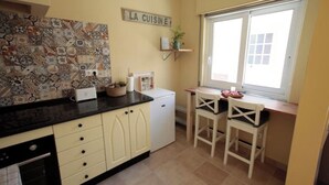 A kitchen with a tiled backsplash, a small refrigerator, a sink, and a window with a view. - Casa Flores. Historic center (Lagos)