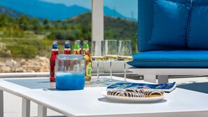 Une table avec des bouteilles, des verres et une assiette de pâtisseries, le tout disposé devant un paysage montagneux pittoresque.