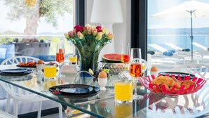Une table de petit-déjeuner avec des assiettes, des verres, un vase de fleurs et un panier de croissants.