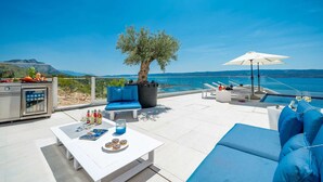 Une terrasse sur le toit avec une piscine, un espace salon et une vue sur la mer.