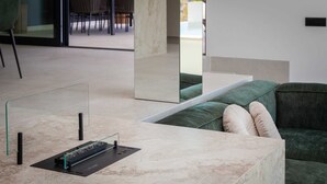 Ein modernes Interieur mit einem мраморнем Empfangstresen, einem grünen Sofa mit Kissen und einer Glastrennwand.