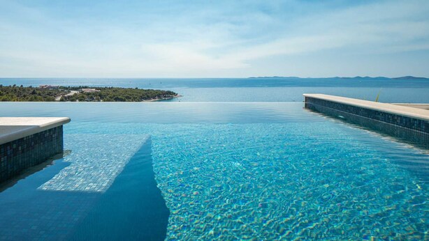 Ein klares, blaues Infinity-Pool mit Blick auf das Meer und eine entfernte Insel.