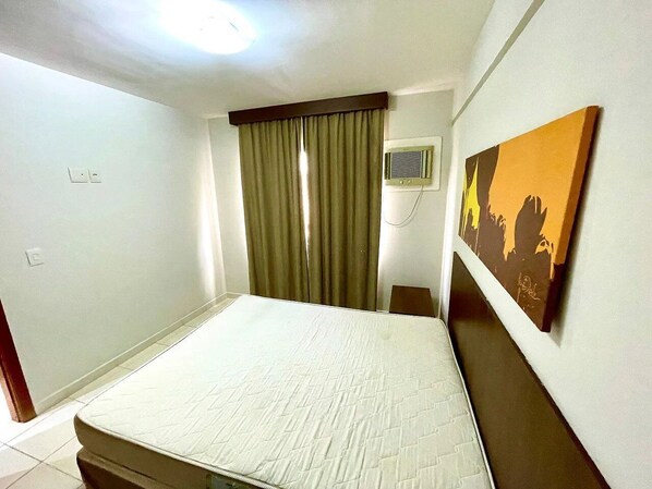 A hotel room with a bed, curtains, a painting on the wall, and a ceiling light.