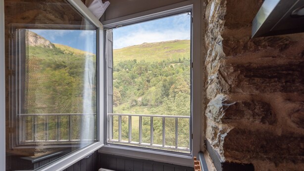 Habitació amb vista a una vall verda a través d'una finestra gran.