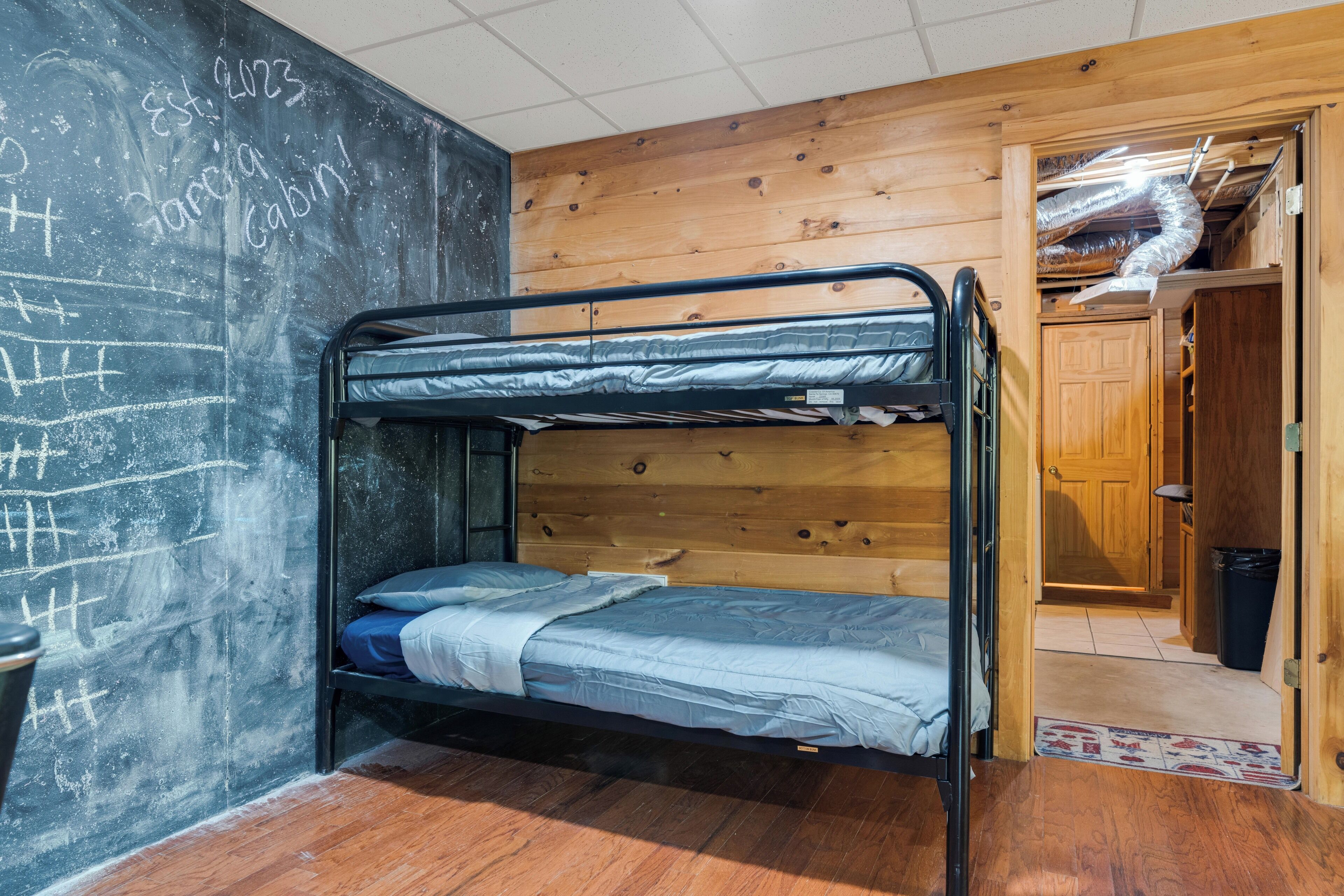 Ein Stockbett in einem Zimmer mit Holzwänden und einer Tafel.