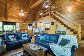 Une cabine spacieuse avec un plafond haut, des murs en bois et un coin salon confortable comprenant deux canapés en cuir, une table à manger et un escalier menant à un niveau supérieur.