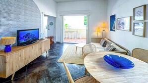 Una sala moderna con televisor, mueble de madera y zona de comedor con mesa y sillas.