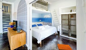 Ein gemütliches Schlafzimmer mit einem Etagenbett, einem Nachttisch aus Holz, einem kleinen Schreibtisch und einem Bücherregal.